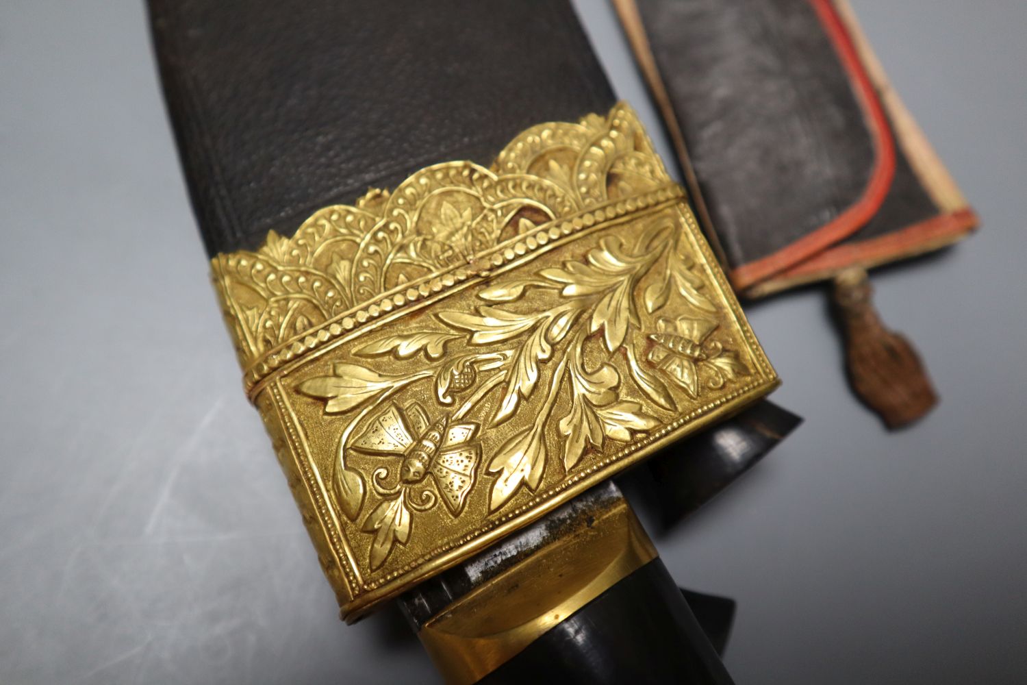 A kukri with skinning knives, leather sheath with elaborate embossed gilt metal mounts, blade 36cm